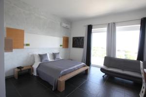 una camera da letto con un letto con una sedia e un divano di Oasis Park Hotel a Torre dell'Orso