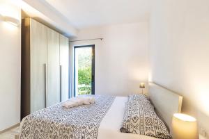 a white bedroom with a bed with a window at Alexander B&B in Tortolì