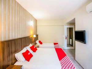 - une chambre avec 2 lits dotés d'oreillers rouges et blancs dans l'établissement OYO Urupema Hotel, São Paulo, à São José dos Campos