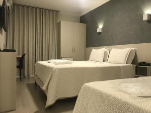 Habitación de hotel con 2 camas con sábanas blancas en Realce Hotel en Jaú
