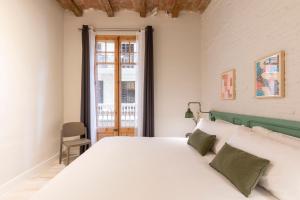 a bedroom with a white bed and a window at Aspasios Gracia Apartments in Barcelona