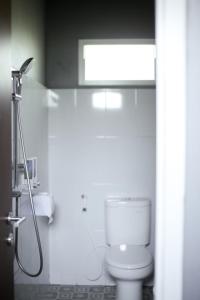 a white bathroom with a toilet and a shower at Keboen Ndalem Homestay in Semarang