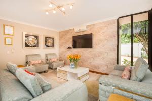 a living room with two couches and a tv at Ekhaya Boutique Hotel in Durban