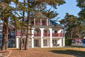 a large white house with red balconies and trees at Résidence Pierre & Vacances Premium Le Domaine de Cramphore in Le Pouliguen