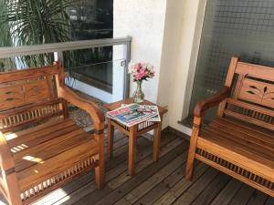 eine Veranda mit zwei Bänken und einem Tisch mit einer Blumenvase in der Unterkunft Realce Hotel in Jaú