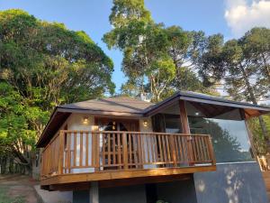 a house with a large deck with trees in the background at Chalés pinha pinhão in Monte Verde