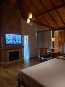 a bedroom with a bed and a flat screen tv at Chalés pinha pinhão in Monte Verde