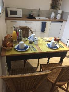 a table with two chairs and a table with cups and plates at Ô Joly Valois in Hauterives
