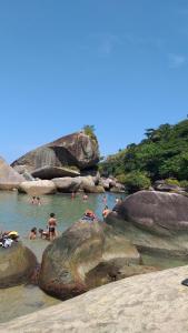een groep mensen in het water op een strand bij Pousada da Helena Trindade in Trindade