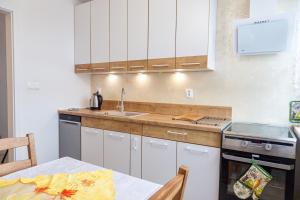a kitchen with white cabinets and a table and a sink at Apartament Yooka in Szczecin