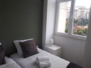 um pequeno quarto com uma cama e uma janela em Coimbra Holiday Residence em Coimbra
