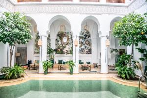 einen Pool in der Lobby eines Gebäudes mit Bäumen in der Unterkunft Riad Palais Calipau in Marrakesch