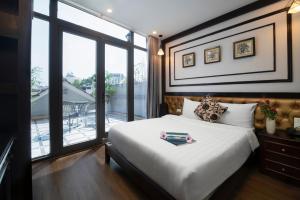 a bedroom with a large bed and a large window at Le Beryl Hanoi Hotel in Hanoi