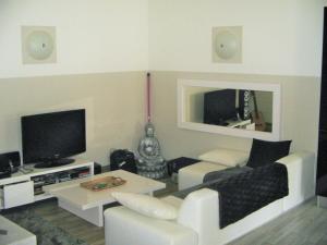 a living room with white furniture and a flat screen tv at Black & White in Alignan-du-Vent