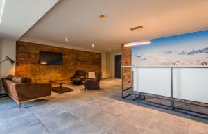 グダウリにあるNew Gudauri, Atrium, 229のレンガの壁にテレビと椅子が備わるロビー
