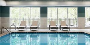 - une piscine avec des chaises et une table dans l'établissement Holiday Inn Express & Suites - Savannah W - Chatham Parkway, an IHG Hotel, à Savannah