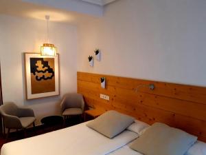 een slaapkamer met een bed en 2 stoelen. bij Pensión Urkia in San Sebastian