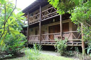 a building with a porch in the middle of a forest at Pousada Canto Verde in Boicucanga