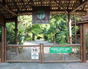 ein Tor mit einem Schild vor einem Park in der Unterkunft Pousada Canto Verde in Boicucanga