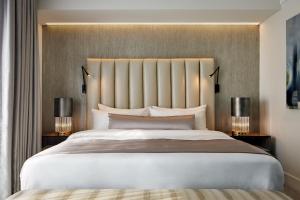 林垦The Kindler Hotel的卧室里有一张白色的大床，床边还有两盏灯 更多15张照片