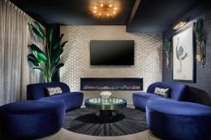 a living room with blue chairs and a tv at The Kindler Hotel in Lincoln