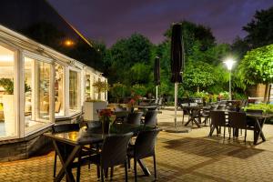 an outdoor patio with tables and chairs and an umbrella at Novotel Maastricht in Maastricht