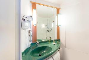 un bagno con un lavandino verde e uno specchio di ibis Luxembourg Sud a Livange