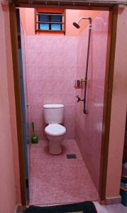 een roze badkamer met een toilet en een douche bij Homestay Zahra Sri Bayu in Kampong Dalam Ru