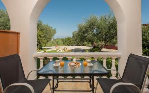 a table on a balcony with two chairs and orange juice at Pansion Mary Studios in Psarou