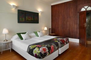 a bedroom with a bed, a dresser and a painting on the wall at Quinta de la Rosa in Pinhão