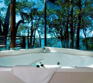 bañera blanca con ventana con árboles en Eumarella Shores Noosa Lake Retreat, en Noosaville