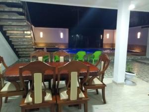 a dining room with a wooden table and green chairs at Hospedaje casa Lucía in Leticia