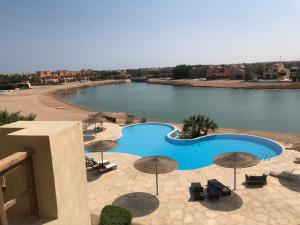 a swimming pool with umbrellas and a body of water at Dar Om Ali ElGouna Sabina y160 2 14 in El Gouna