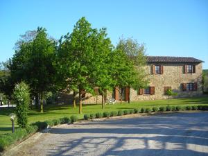una casa de piedra con árboles al lado de una carretera en Agriturismo Casagrande, en Montepulciano