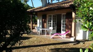 ein kleines Haus mit einem Tisch und einem rosa Stuhl in der Unterkunft Maison dans Quartier Calme in Lacanau-Océan