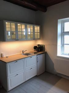 cocina con armarios blancos, fregadero y ventana en Agerfeld gl. skole, en Holstebro