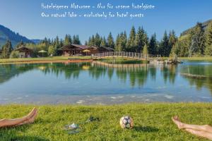 une personne assise sur l'herbe près d'un lac dans l'établissement Apparthotel Talhof, Restaurant, Pool und Spa, à Oberau