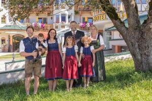 a family posing for a picture in front of a tree at Apparthotel Talhof, Restaurant, Pool und Spa in Oberau