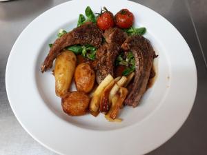 a plate of food with meat and potatoes and strawberries at L'Horizon des Landes in Doazit