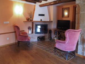 sala de estar con 2 sillas y chimenea en Casa Torralba, en El Frago