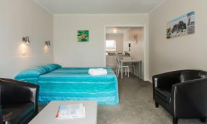 a bedroom with a bed and a table and chairs at Averill Court Motel in Paihia