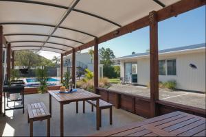 eine Terrasse mit einem Tisch, Bänken und einem Pool in der Unterkunft Averill Court Motel in Paihia