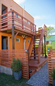 a wooden deck with a spiral staircase in front of a house at Aparts Dunas de Valizas in Barra de Valizas
