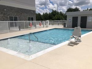 una gran piscina con una silla y una silla en Holiday Inn & Suites - Fayetteville W-Fort Bragg Area, an IHG Hotel, en Fayetteville