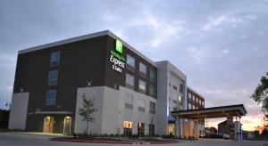 Un edificio negro con un cartel verde encima. en Holiday Inn Express & Suites McKinney - Frisco East by IHG, en McKinney