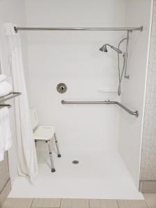 a white bathroom with a shower with a chair at Holiday Inn Express Edgewood-Aberdeen-Bel Air in Edgewood