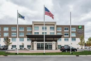 un immeuble de bureaux avec deux drapeaux devant lui dans l'établissement Holiday Inn Express & Suites Allen Park, an IHG Hotel, à Allen Park