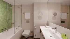 a bathroom with a toilet, sink, and bathtub at Holiday Inn Frankfurt - Alte Oper, an IHG Hotel in Frankfurt