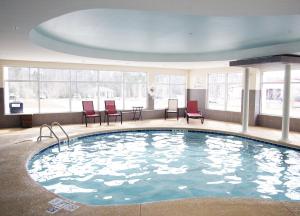 una grande piscina con sedie rosse in un edificio di Holiday Inn Express & Suites Havelock Northwest New Bern, an IHG Hotel a Havelock