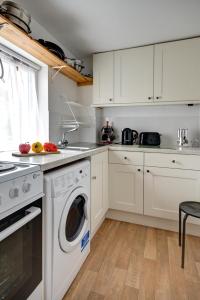 サイレンセスターにあるKatrinas Apartment By Treetop Propertyの白いキャビネットと食器洗い機付きのキッチンが備わります。